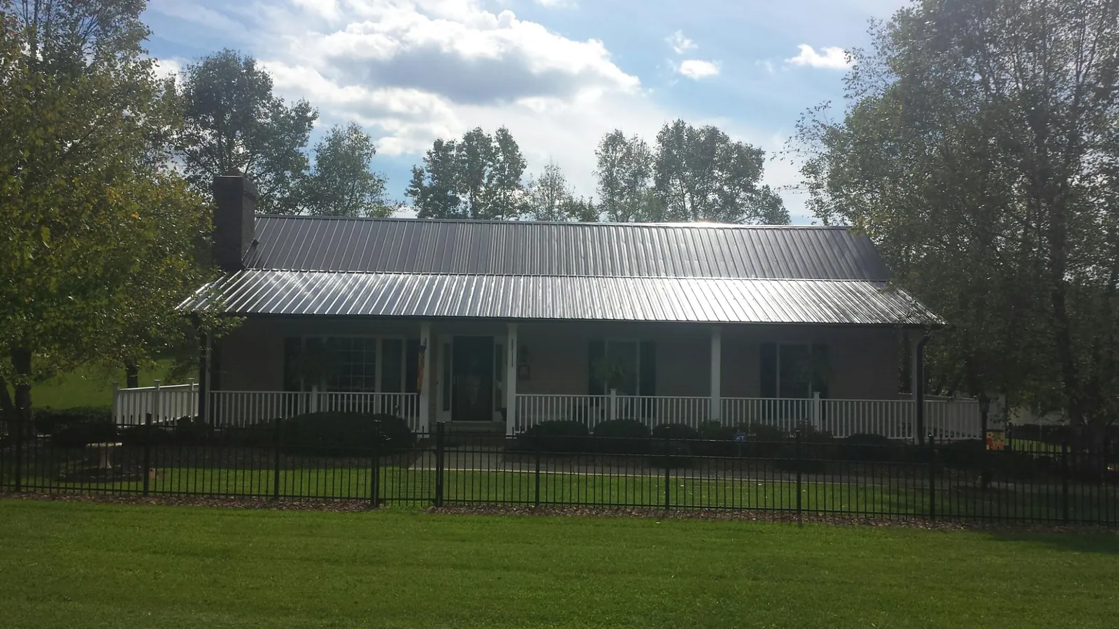 Gray metal roof on a brick ranch with a full width front porch — Gutter Guard Installation work by our crew in Silver Lake