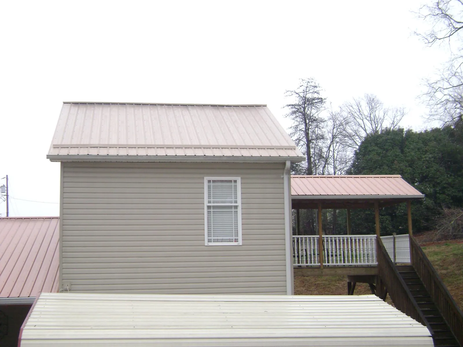 Tan metal roofs on a two story addition and attached porch, from a Roof Replacement job in Silver Lake